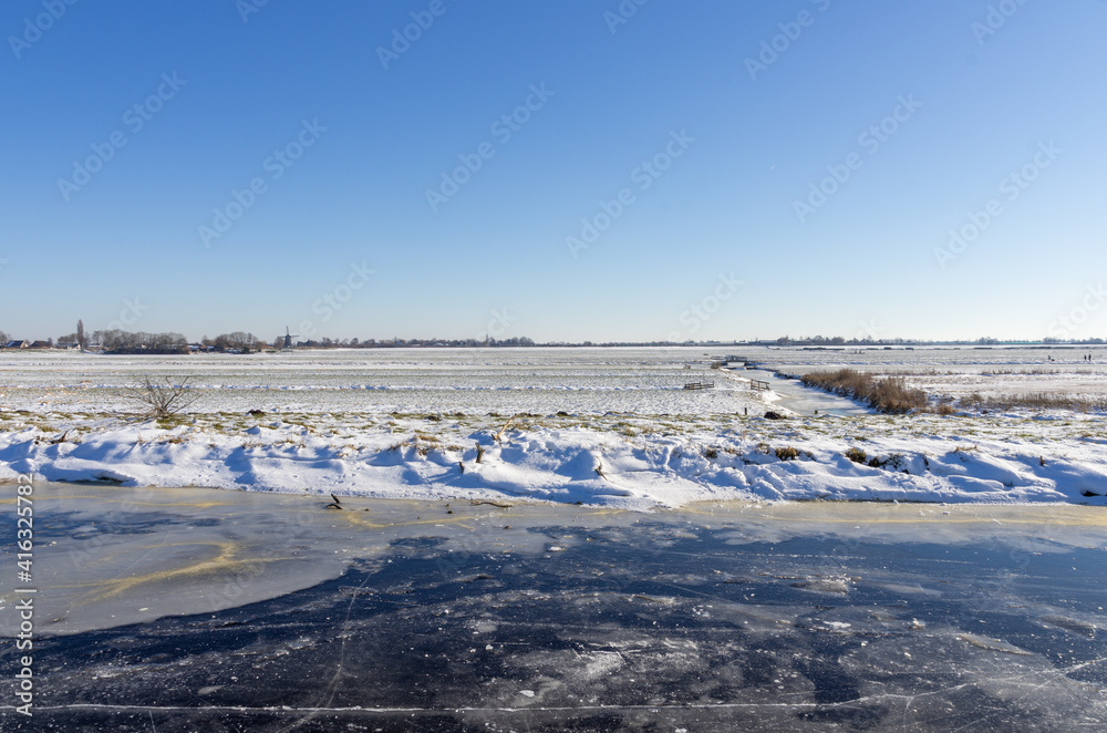 frozen and snowy Dutch landscape with clear blue sky