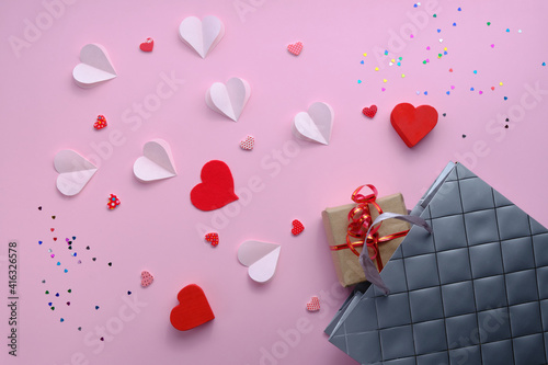 Grey paper bag, red and pink hearts and gift on white background. Valentine day concept.