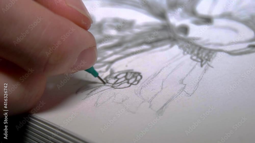 Person sketching with a green pencil on a white paper. Close up shot