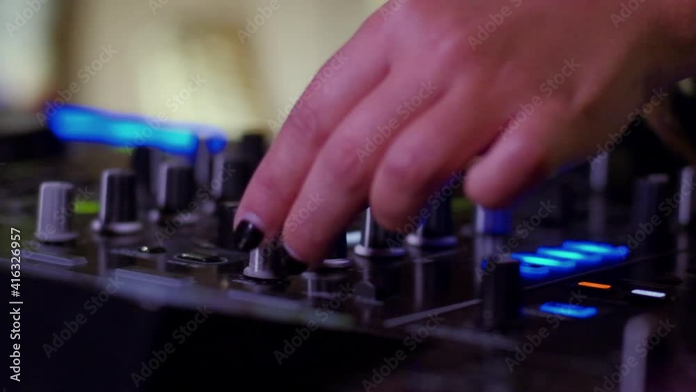 Slow motion close-up of DJ with painted fingernails turning the knobs on her DJ mixer Slow motion close-up of DJ with painted fingernails turning the knobs on her DJ mixer