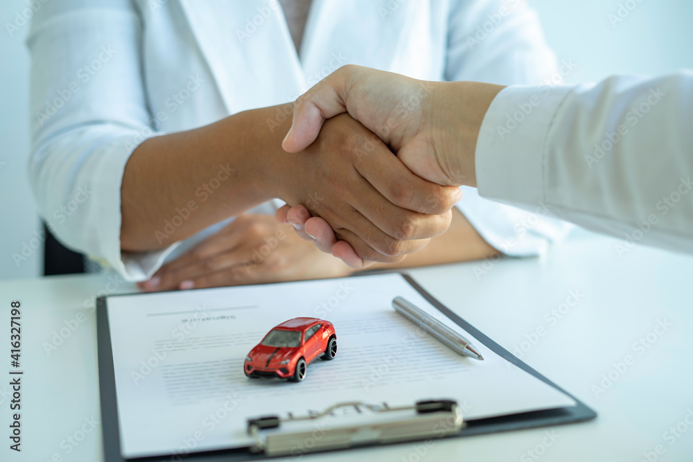 Insurance agent joins hands with the insured after proposing the concept of car insurance. And contract insurance concept agreement Making rental and purchase agreements for cars