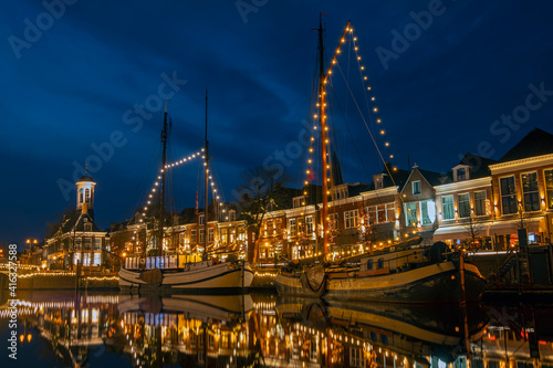 Traditional boats in the harbor from Dokkum in the Netherlands in christmas time at twilight