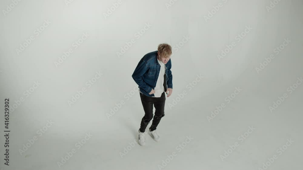 Teenager Enjoying his favorite music. Cheerful young man in headphones listening to the music dancing and gesturing Teenager Enjoying his favorite music. Cheerful young man in headphones listening to the music dancing and gesturing