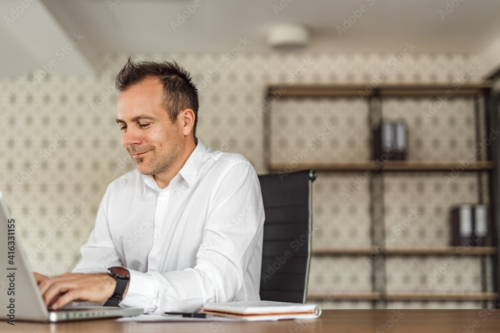 Positive manager typing on laptop in bright office, portrait, copy space. Positive manager typing on laptop in bright office, portrait, copy space.