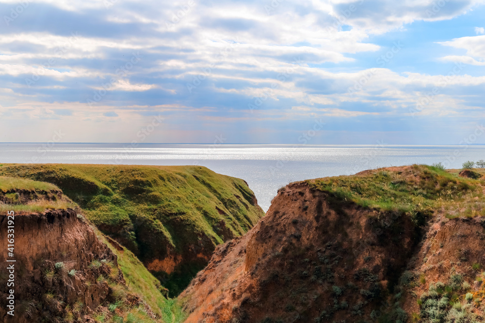 Landscape view clay cape mountains and cliffs near blue sea and skyline. Seascape of coast from green meadows. Clay rock in front of sea. Sea view horizon. Secluded nature tourism