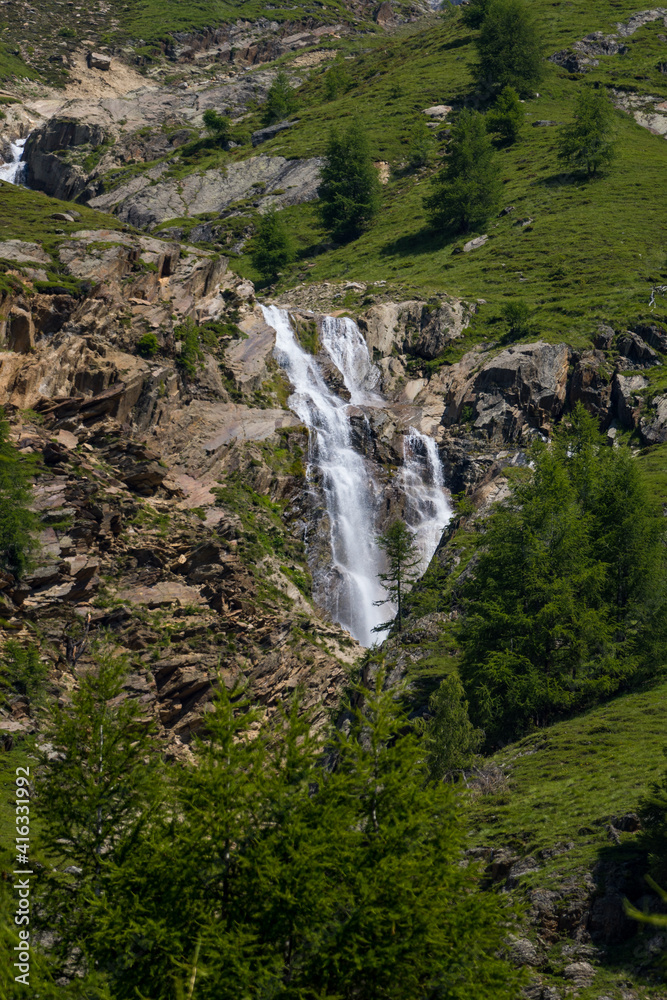 mountain stream with small waterfall in wide alpine field