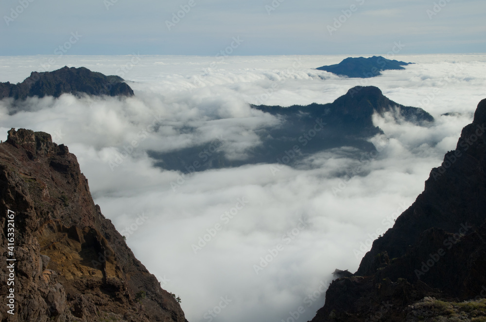 Volcanic crater covered by a sea of clouds. Caldera de Taburiente National Park and Cumbre Vieja in the background. La Palma. Canary Islands. Spain.