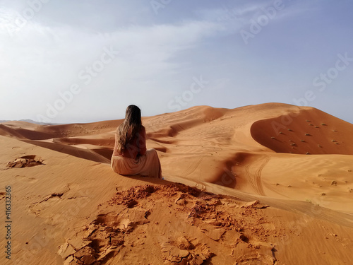 Woman sitting in a dune in the sahara desert