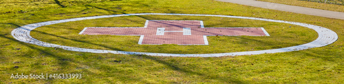 Auf einer grünen Wiese befindet sich der Landeplatz für einen Hubschrauber.