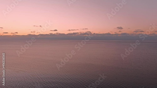 Sunset in a calm sea with frozen seashore. Shot from drone
