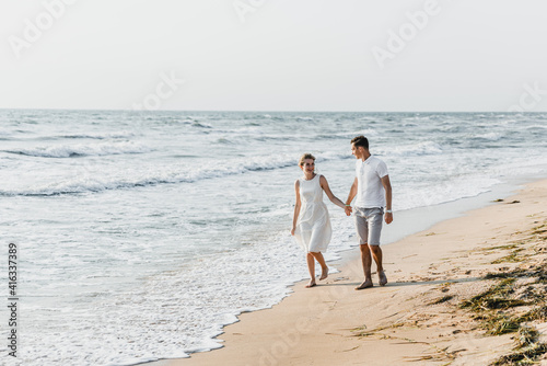 beautiful loving couple walks on the seashore. happy young couple spend time on the beach. honeymoon newlyweds. guy with girl at dawn of the day. couple on vacation. summer rest. couple hugging © Vadym