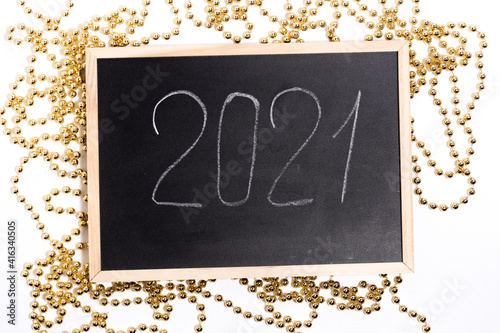 A chalk plaque with the inscription 2021, around the golden beads. New Year's Eve