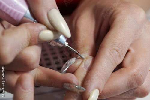 female manicure  master treats nails with an electric nail file