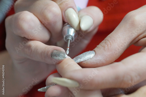 female manicure  master treats nails with an electric nail file