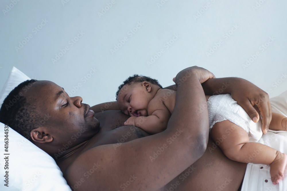 Father lying on bed holds his baby daughter, 4 mouth baby on his chest, man is not wearing a shirt Father lying on bed holds his baby daughter, 4 mouth baby on his chest, man is not wearing a shirt