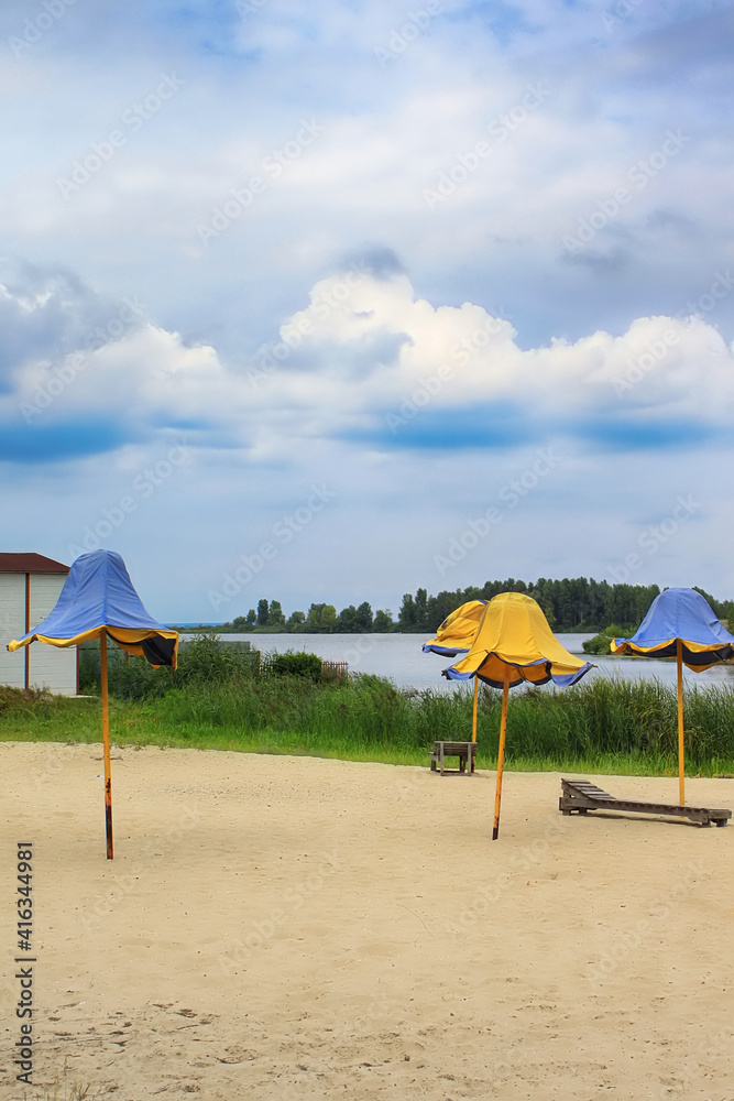 Fototapeta premium Beautiful beach with tents in the form of tulips in colors of national flag (blue and yellow) and the Dnieper River in town of Ukrainka, Kyiv region, Ukraine
