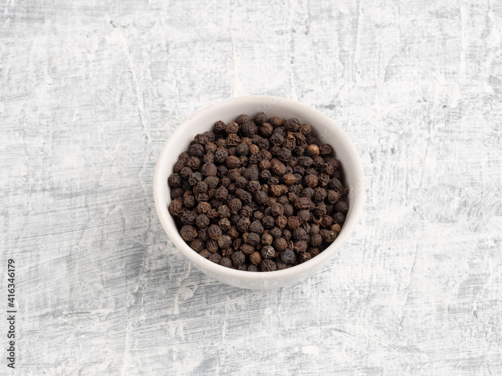 Spice black pepper in ceramic bowl on a white concrete background Spice black pepper in ceramic bowl on a white concrete background