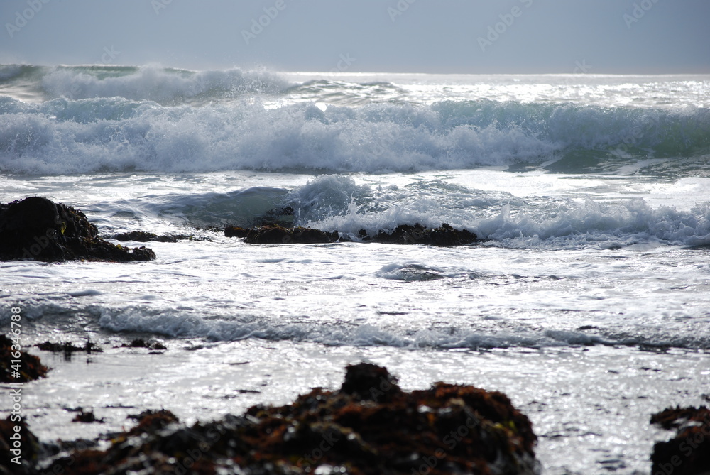 ocean and coastline with roaring waves over rocks and blue sky 