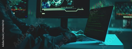 Female Hacker working on laptop at night in the modern workspace. Female Hands are typing a code at keyboard or hacking a website. photo