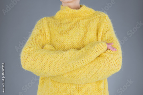 Close up hands of yang woman in yellow sweater. People concept. Grey background