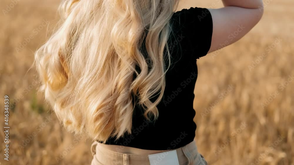 Carefree young woman in slow motion video walking on field wheat enjoying freedom and calmness on rural nature during vacations holidays. Concept of harvest. Farming.