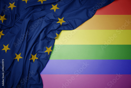 waving national flag of european union on a gay rainbow flag background.