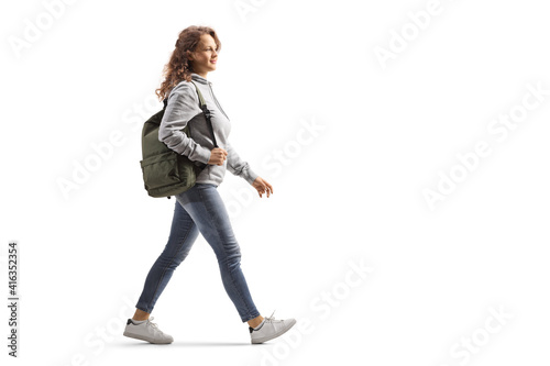 Full length profile shot of a female student in jeans with a backpack walking