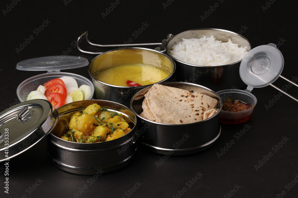 Typical Stainless steel Lunch Box or Tiffin with Maharashtrian food menu Chapati OR Roti, Plain Dal Tadka, White Rice Potato sabji with salad and pickle