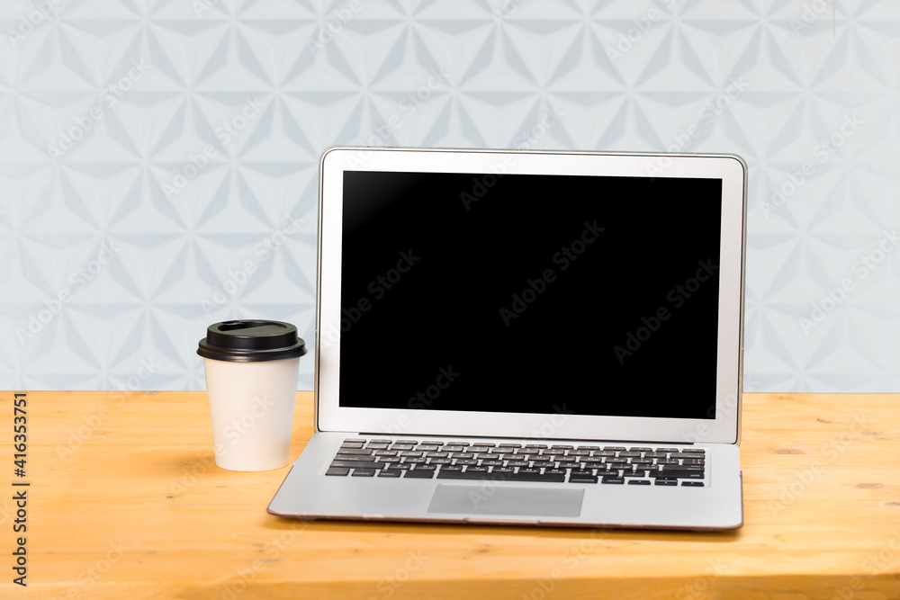 Mockup blank laptop screen with coffee on wooden table in coworking space. Mockup blank laptop screen with coffee on wooden table in coworking space.
