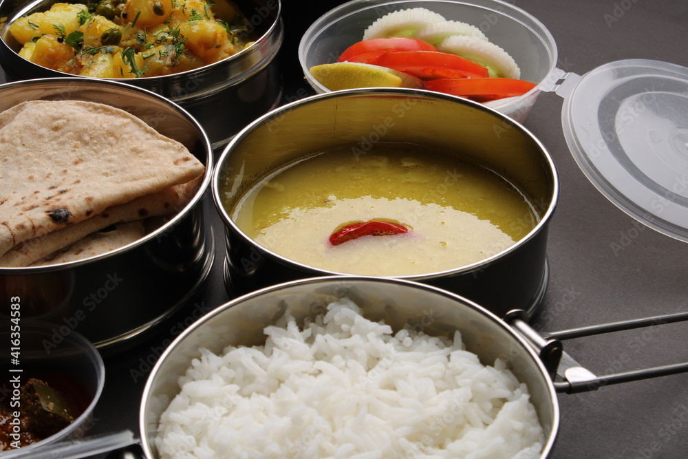 Typical Stainless steel Lunch Box or Tiffin with Maharashtrian food menu Chapati OR Roti, Plain Dal Tadka, White Rice Potato sabji with salad and pickle