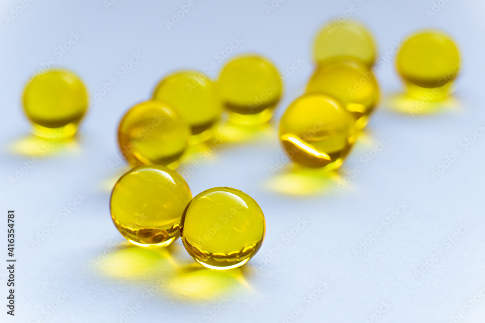 Round tablets of vitamins A and E on a white background. Scattered pills close-up. Round yellow capsules lie on the table. Round tablets of vitamins A and E on a white background. Scattered pills close-up. Round yellow capsules lie on the table.