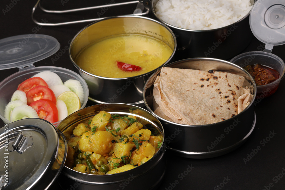 Typical Stainless steel Lunch Box or Tiffin with Maharashtrian food menu Chapati OR Roti, Plain Dal Tadka, White Rice Potato sabji with salad and pickle