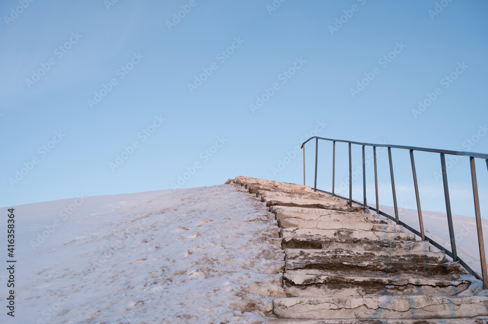 Stairs on a snow-covered hill. Rezekne city in Latvia. Blue sky.