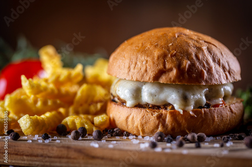 Craft beef burger with cheese and french fries on wooden background