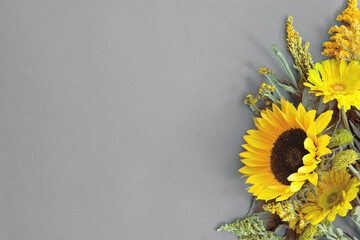 Border of different fresh bright illuminating yellow summer flowers lying on trendy gray background. Flat lay style. Copy space. 2021 color trend