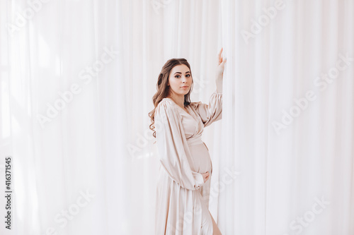 pregnancy, rest, people and expectation concept - happy pregnant woman touching her belly at home