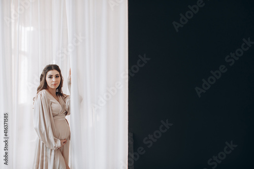 pregnancy, rest, people and expectation concept - happy pregnant woman touching her belly at home © ALEXSTUDIO