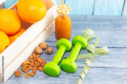 Lots of oranges and a bottle of juice, measuring tape on a wooden textured background. Fitness, sports nutrition. photo