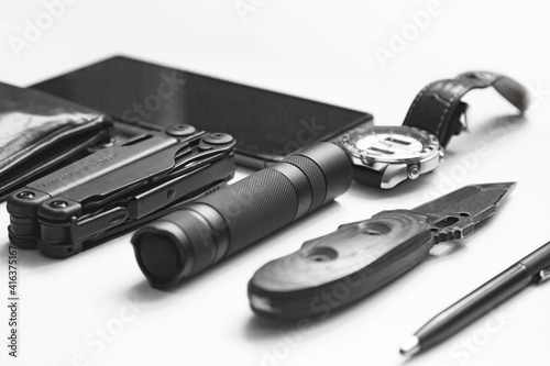 Top view of everyday  carry ( EDC ) items for men in black color on white background -  flashlight, watch,  multi tool  multitool, phone, pen. Modern city set. Minimal concept. Vintage colored picture photo