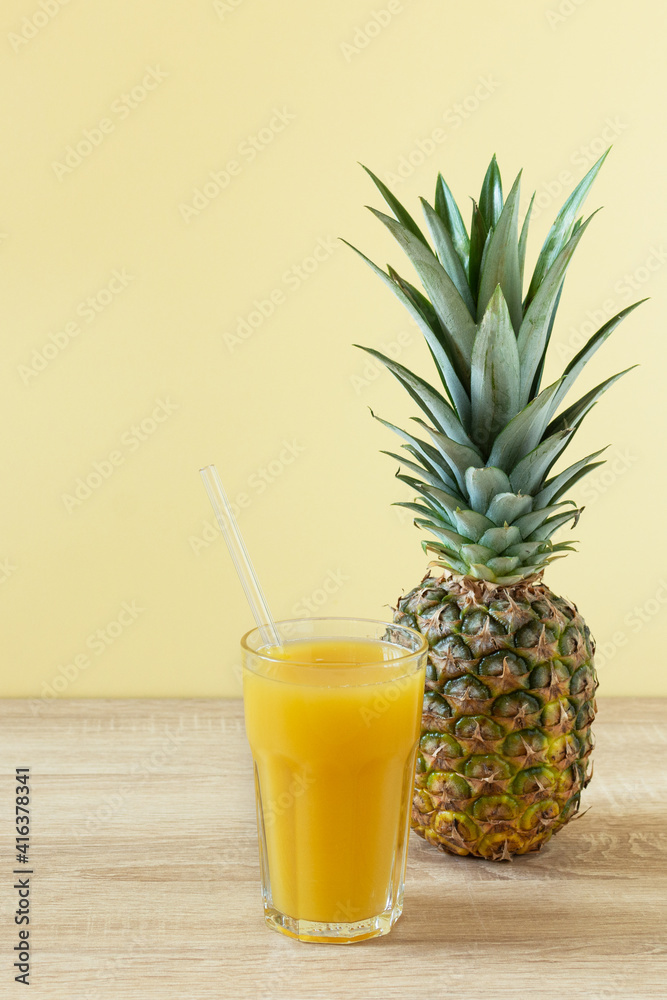 Pineapple fresh juice in glass on wooden table over yellow background. Pineapple fresh juice in glass on wooden table over yellow background.