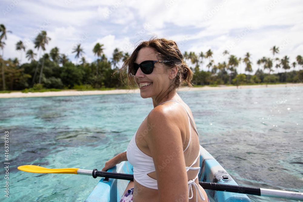 Smiling woman on kayak looking back near tropical island Moorea