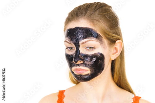 Woman applying black cleanser mask to face