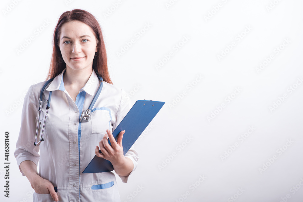 Portrait of a young female doctor in a white uniform with a folder in hands in the studio on a white background with copyspace Portrait of a young female doctor in a white uniform with a folder in hands in the studio on a white background with copyspace