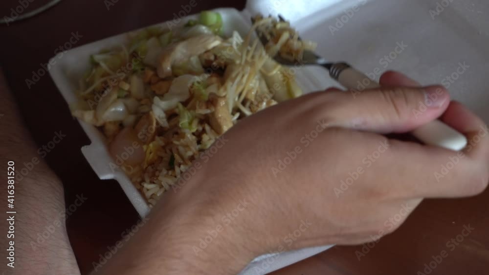 close up of a man eating chaufa, typical Peruvian fast food in a disposable plastic container in his room close up of a man eating chaufa, typical Peruvian fast food in a disposable plastic container in his room