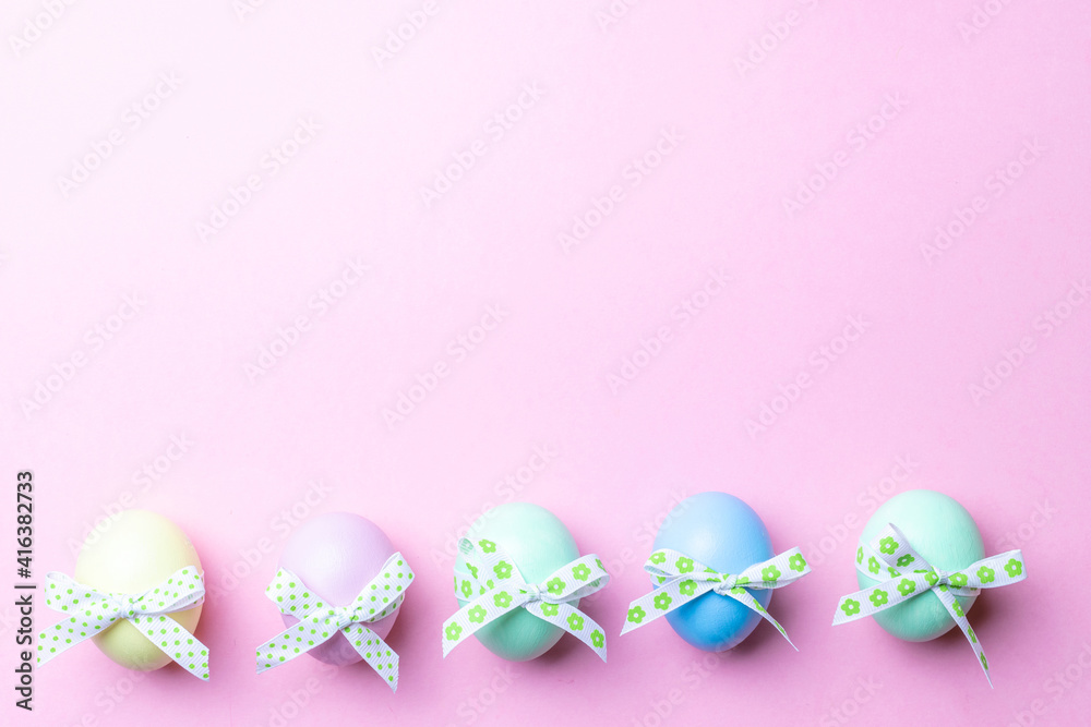 Easter egg hunt. Colorful egg with tape ribbon on pastel pink background in Happy Easter decoration. Traditional design in top view.