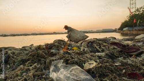 Pemulung berjalan di tumpukan sampah tepi pantai / Scavengers walk on the pile of trash by the beach 2 photo