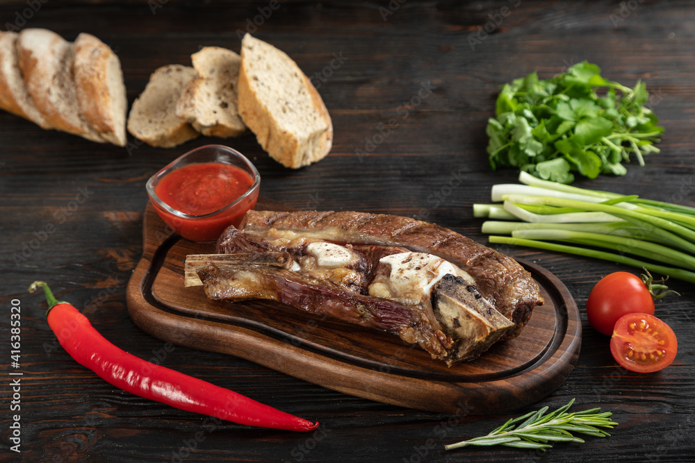 Roasted beef on the bone on a board for serving.