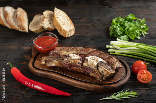 Obraz na płótnie Roasted beef on the bone on a board for serving. w salonie