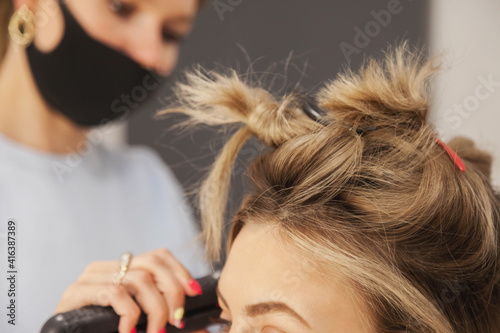 Hairdresser does hairstyle cute pretty young woman in beauty salon. Customer service in interior room create an amazing image. Work hairstyles creation wizard. Concept style, satisfaction. Copy space