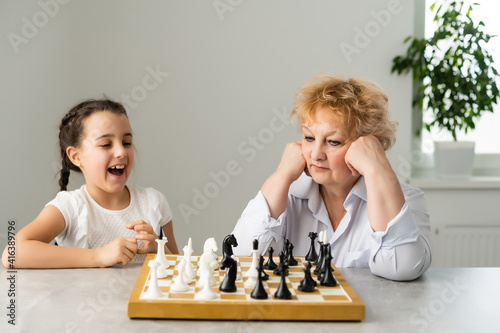 Grandmother and young girl playing chess together at home